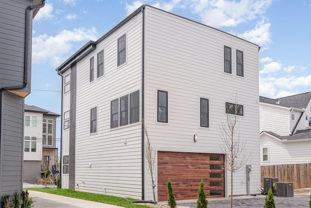 exterior space with fence, cooling unit, and a garage