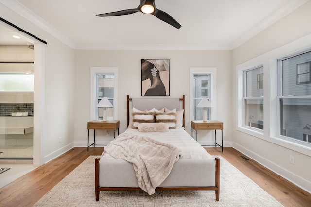 bedroom with crown molding, a ceiling fan, visible vents, wood finished floors, and baseboards