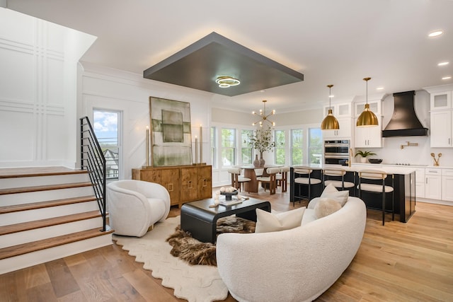 living area with light wood finished floors, an inviting chandelier, recessed lighting, and stairs