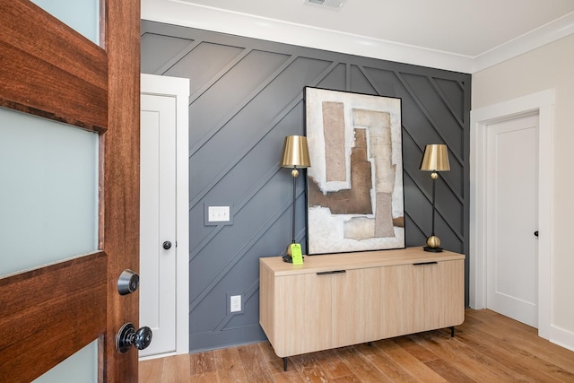 interior details featuring wood finished floors, visible vents, and a decorative wall