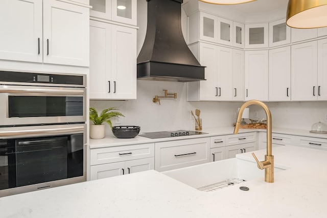 kitchen featuring white cabinets, double oven, premium range hood, and black electric stovetop