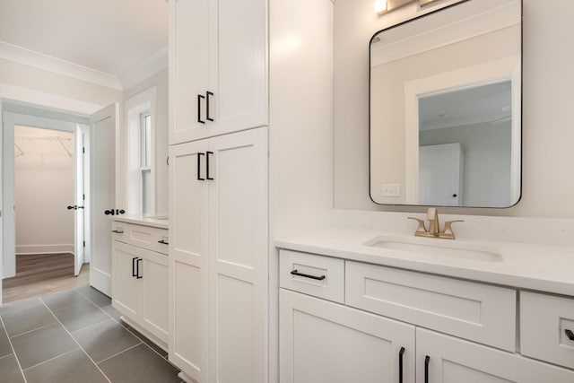bathroom with a spacious closet, vanity, ornamental molding, and tile patterned flooring