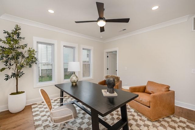 office space with visible vents, baseboards, ornamental molding, a ceiling fan, and light wood-style flooring