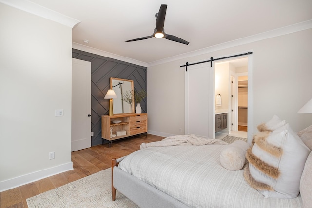 bedroom with baseboards, a barn door, ceiling fan, crown molding, and wood finished floors