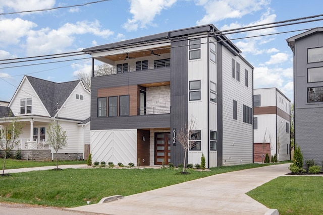view of front of house featuring board and batten siding, ceiling fan, and a front yard