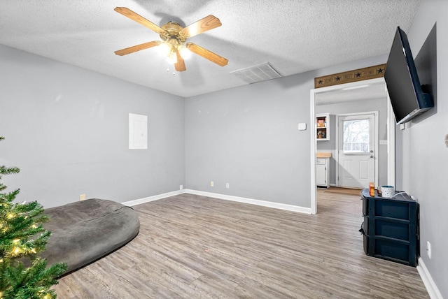 living area featuring baseboards, a textured ceiling, visible vents, ceiling fan, and wood finished floors