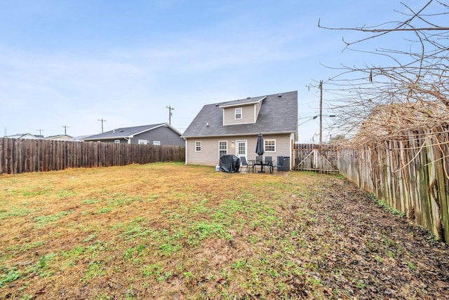 rear view of property with a yard, a fenced backyard, and central AC