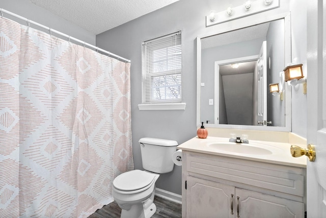 full bath featuring a textured ceiling, vanity, toilet, wood finished floors, and baseboards