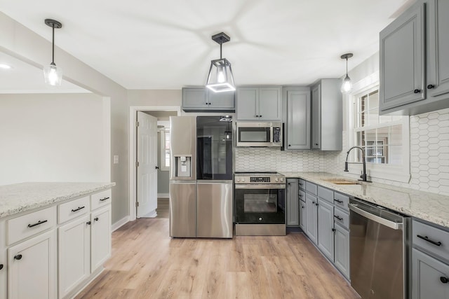 kitchen featuring gray cabinetry, a sink, backsplash, and appliances with stainless steel finishes