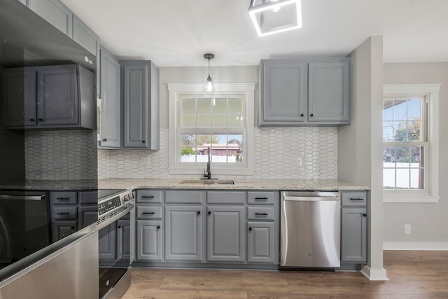 kitchen featuring decorative backsplash, a sink, stainless steel appliances, and gray cabinetry