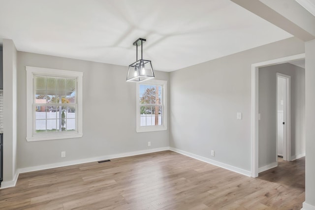 unfurnished dining area featuring visible vents, light wood-style flooring, and baseboards