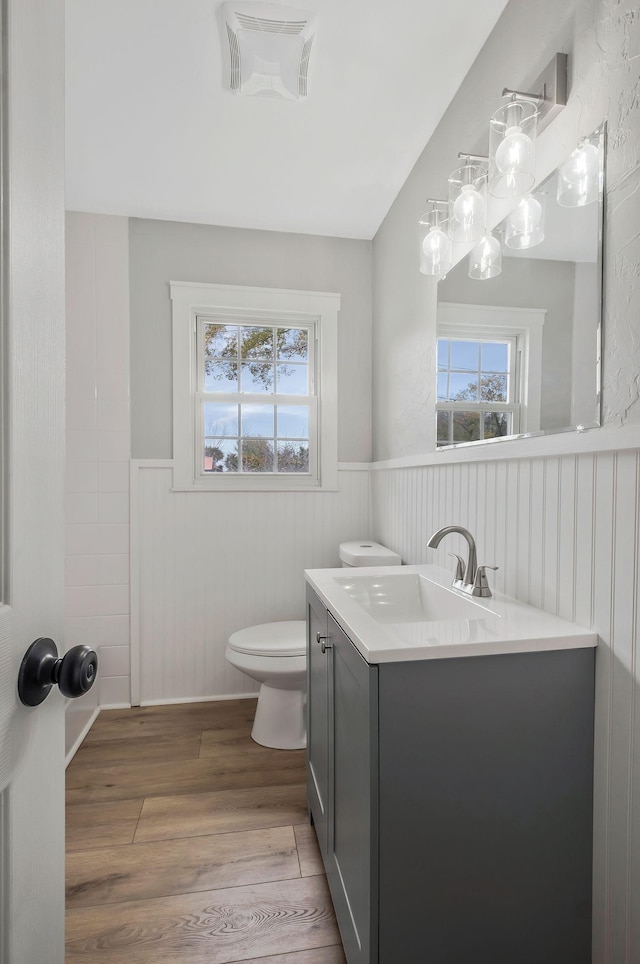 bathroom featuring wood finished floors, visible vents, toilet, vanity, and wainscoting