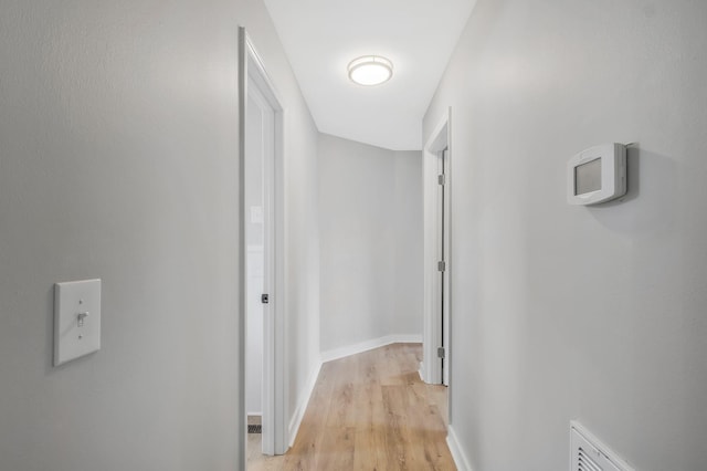corridor featuring visible vents, light wood finished floors, and baseboards