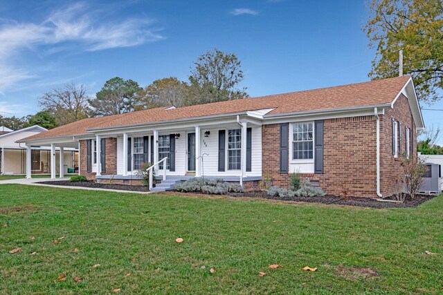 single story home featuring brick siding, a porch, a front yard, and an attached carport