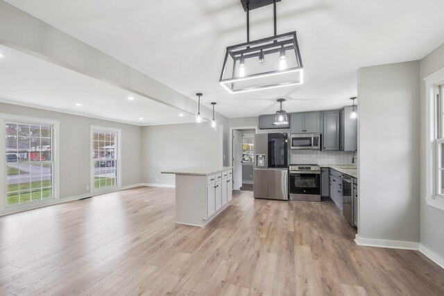 kitchen with stainless steel appliances, backsplash, gray cabinets, light wood-type flooring, and baseboards