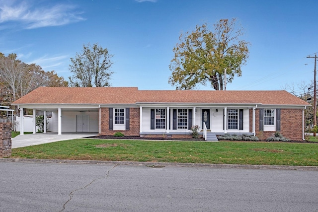 single story home featuring a front lawn, concrete driveway, covered porch, an attached carport, and brick siding