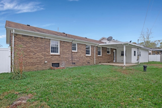 rear view of house featuring brick siding, a yard, a patio, and fence
