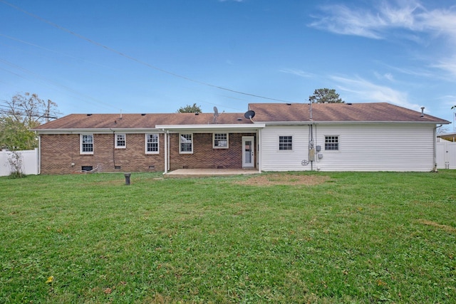 back of property featuring brick siding, a patio area, a lawn, and fence