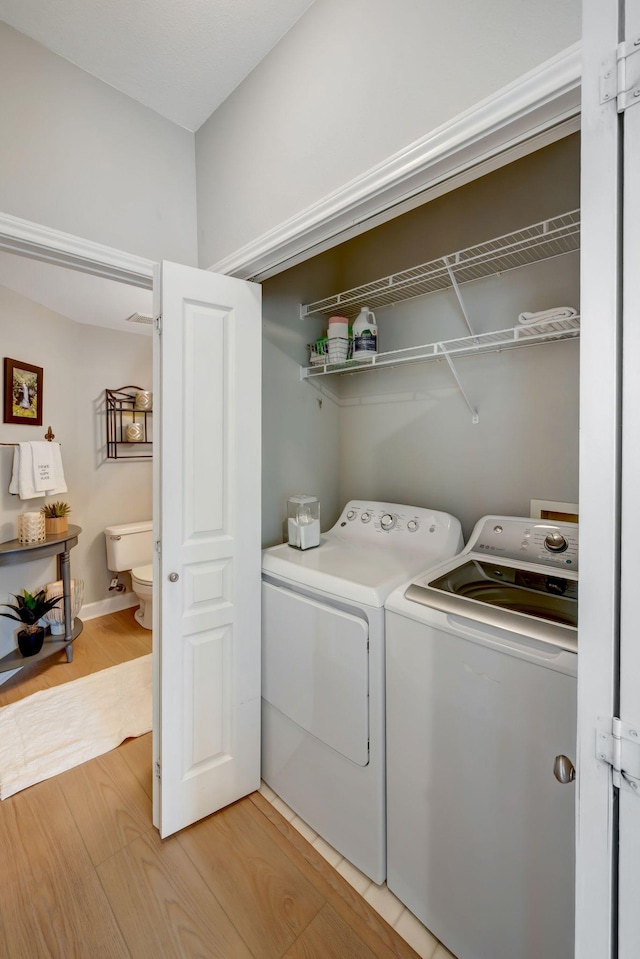 laundry room featuring light wood-type flooring, separate washer and dryer, and laundry area