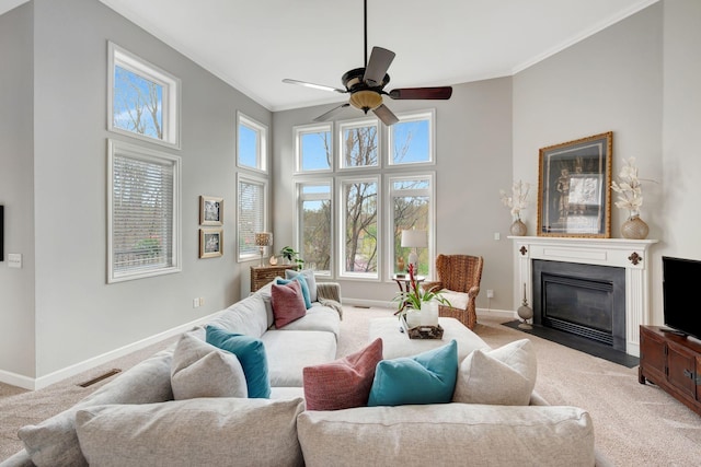 carpeted living area with a fireplace with flush hearth, crown molding, baseboards, and visible vents