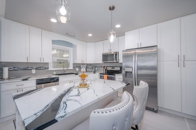 kitchen with a kitchen island, a sink, backsplash, and appliances with stainless steel finishes