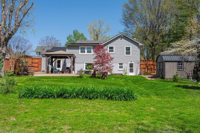 rear view of house featuring a shed, a gazebo, fence, an outbuilding, and a wooden deck