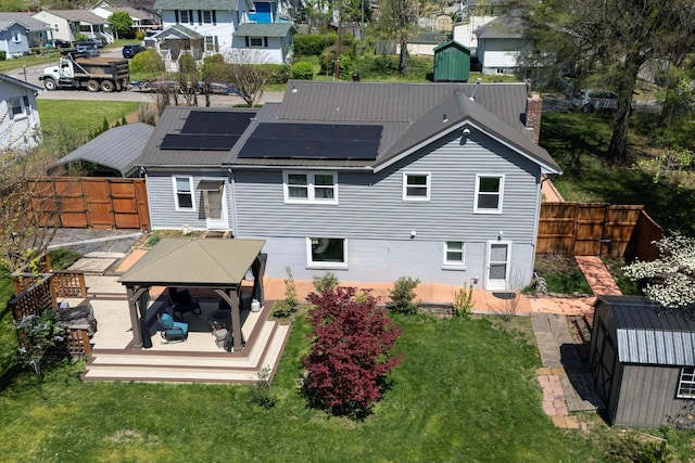 back of property with a fenced backyard, a chimney, a patio, solar panels, and a gazebo