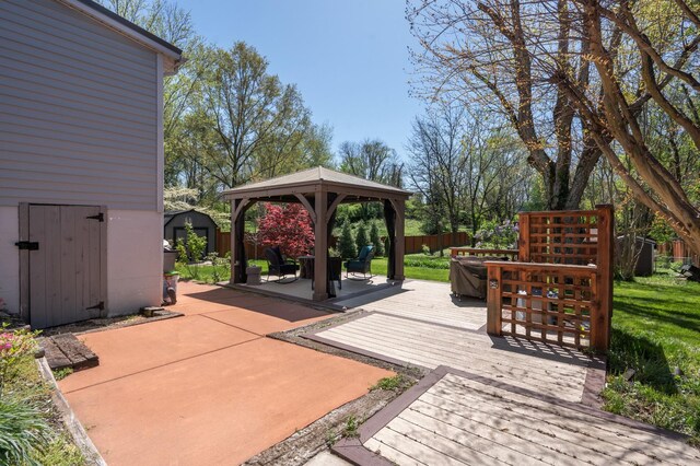 view of patio with a wooden deck, a shed, an outdoor structure, fence, and a gazebo
