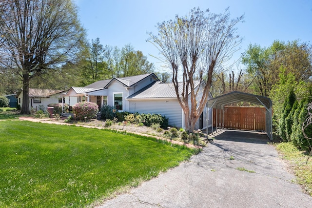 ranch-style house with a standing seam roof, a carport, metal roof, a front lawn, and driveway