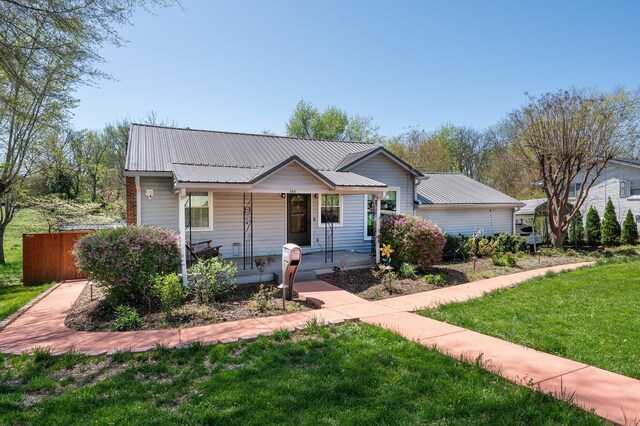 view of front of home with a porch, metal roof, and a front lawn
