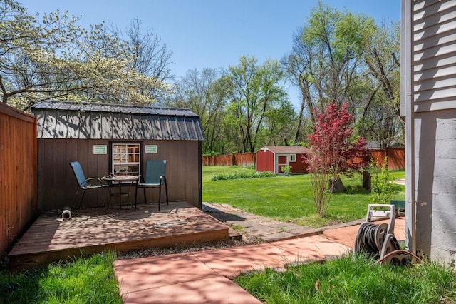 view of yard with a shed, a fenced backyard, an outdoor structure, and a wooden deck