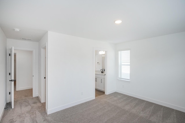 empty room featuring baseboards, a sink, visible vents, and light carpet