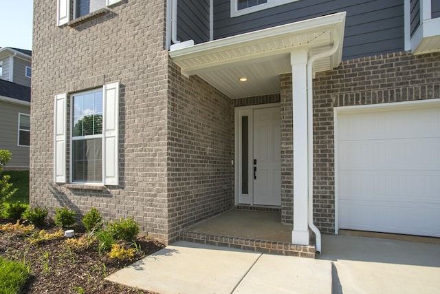 doorway to property featuring brick siding and a garage