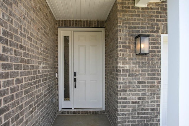 view of exterior entry featuring brick siding