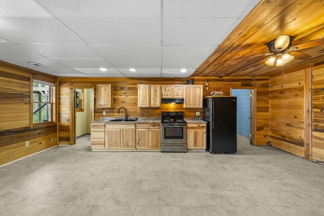 kitchen with freestanding refrigerator, under cabinet range hood, wood walls, a sink, and electric stove