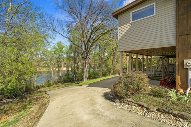 exterior space with a water view, driveway, and stairs