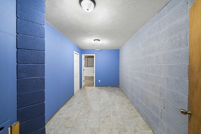hallway with a textured ceiling and concrete block wall