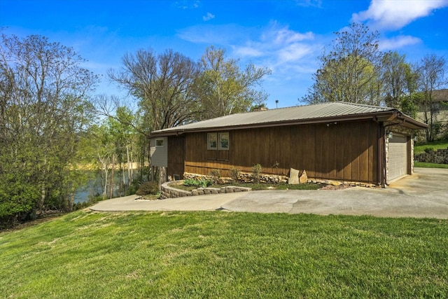 exterior space with a yard, metal roof, and driveway