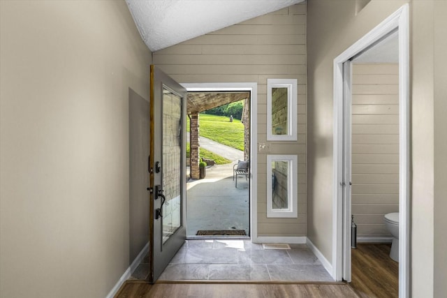entrance foyer with lofted ceiling, a textured ceiling, baseboards, and wood finished floors
