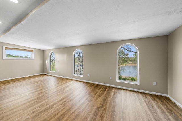 unfurnished room featuring baseboards, wood finished floors, and a textured ceiling