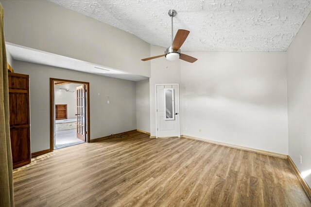 empty room with wood finished floors, ceiling fan, baseboards, and vaulted ceiling