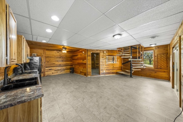 interior space featuring wooden walls, a paneled ceiling, and a sink