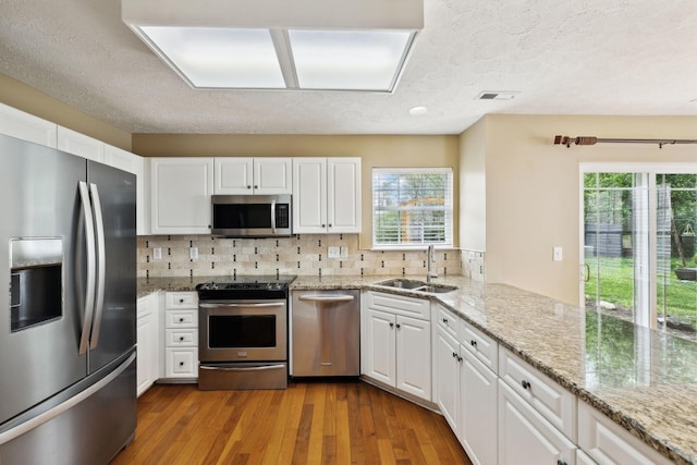 3227 Gardendale Dr, Franklin, TN 37064 - kitchen featuring white cabinets, stainless steel appliances, wood finished floors, a sink, and decorative backsplash
