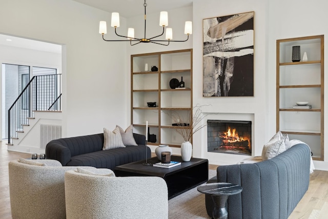 6004 Jocelyn Hollow Rd, Nashville, TN 37205 - living area with visible vents, an inviting chandelier, a warm lit fireplace, wood finished floors, and stairs