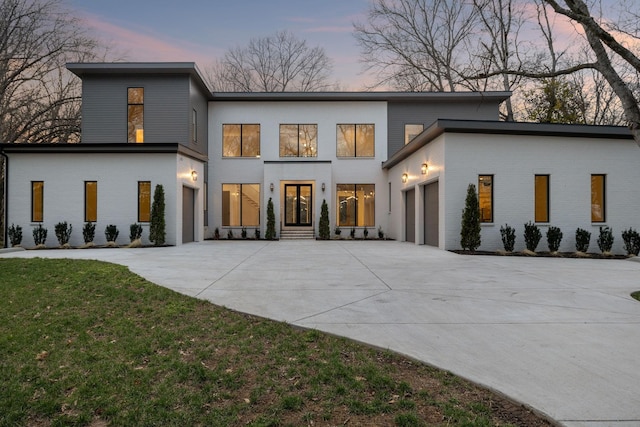 6004 Jocelyn Hollow Rd, Nashville, TN 37205 - back of property at dusk featuring concrete driveway, brick siding, an attached garage, and a lawn