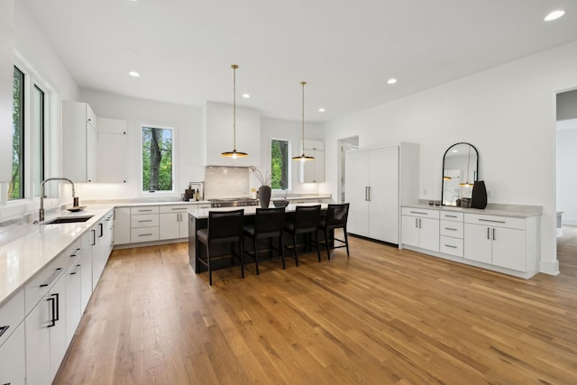 6004 Jocelyn Hollow Rd, Nashville, TN 37205 - kitchen featuring a center island, white cabinets, light wood-style floors, a breakfast bar area, and a sink