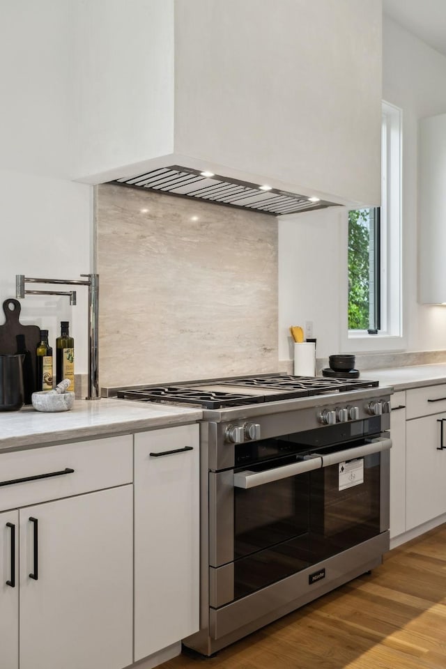 6004 Jocelyn Hollow Rd, Nashville, TN 37205 - kitchen with high end stainless steel range oven, premium range hood, light countertops, white cabinets, and decorative backsplash