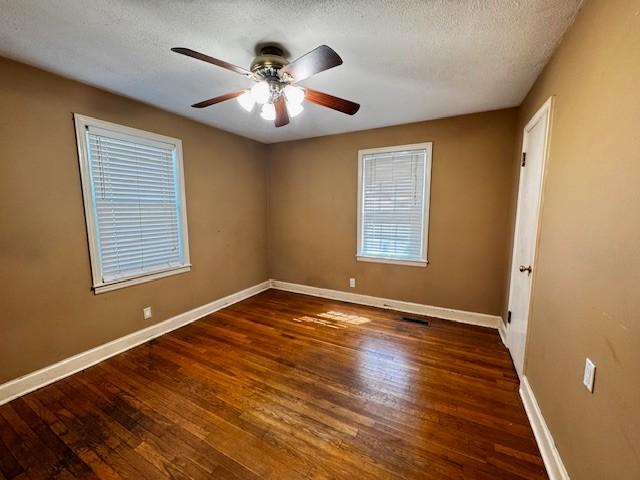 unfurnished room with ceiling fan, baseboards, a textured ceiling, and wood finished floors