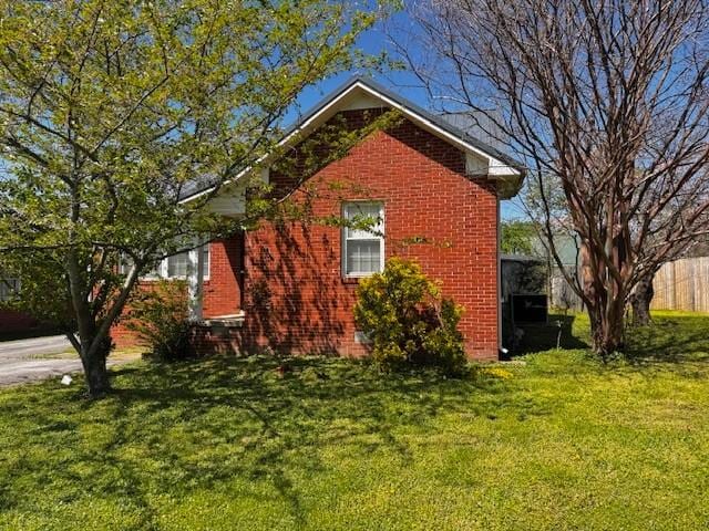 view of side of property featuring a lawn and brick siding