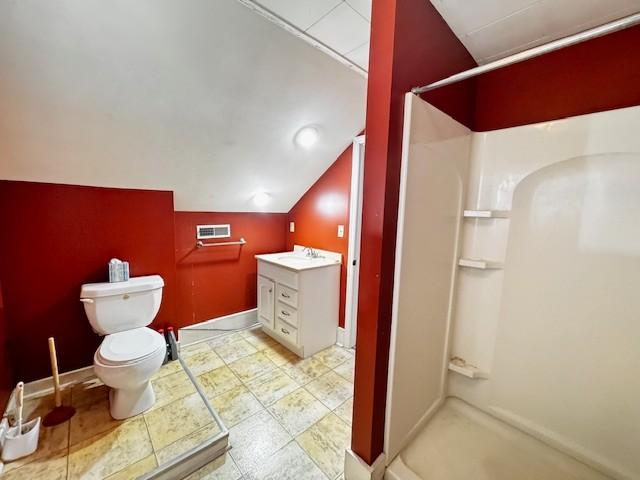 bathroom with a shower stall, vanity, vaulted ceiling, toilet, and baseboards
